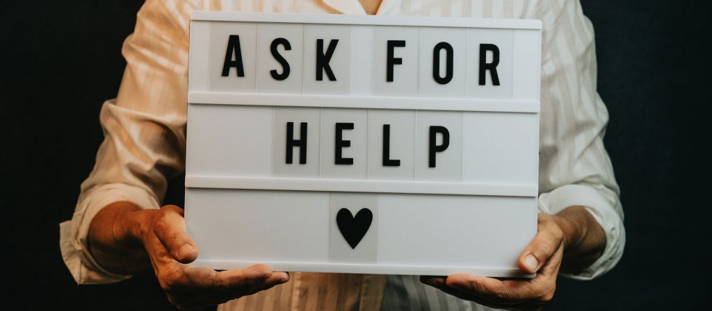 Person holds a sign that says ask for help
